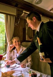 luxury tour peru, a waiter serving a glass of wine in a luxurious train